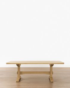 a wooden table sitting on top of a hard wood floor next to a white wall