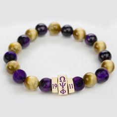 Beautiful Handmade Bracelet Features Various Shades Of Natural Stone Purple And Golden Amber Beads With A Bold Golden Centerpiece On A Sturdy Stretchable Elastic Band That Will Fit Most Wrists. The Centerpiece Is Made Of 3 Pieces That Feature Omega Psi Phi In Greek Letters In The Center And 1911 On Either Side It Is A Subtle Piece That Is Perfect For Everyday Wear. Makes A Great Gift! Omega Psi Phi, Golden Amber, Greek Letters, Amber Beads, Mens Accessories Jewelry, Handmade Bracelet, Bead Bracelet, Purple Gold, Handmade Bracelets