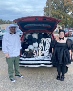 two people standing in front of a car trunk