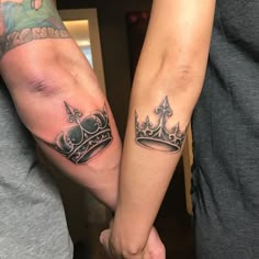 two people holding hands with tattoos on their arms, one has a crown and the other has a cross