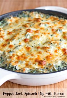 a casserole dish with cheese and spinach in it on a wooden table