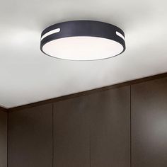 a circular light fixture in a kitchen with wooden cabinets and cupboards on the wall