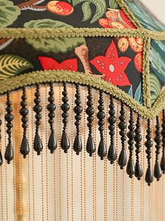 a close up of a lamp shade with beads hanging from it's bottom and sides