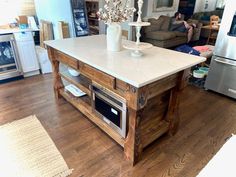 a kitchen island made out of pallet wood with a white marble top and stainless steel appliances