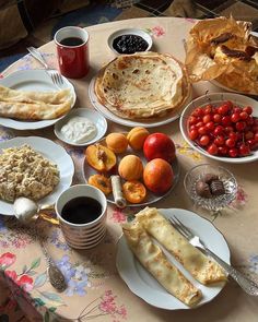 a table topped with plates of food and cups of coffee on top of a table