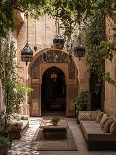 an outdoor living area with couches, tables and hanging lights on the wall above