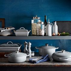 several pots and pans sitting on top of a shelf next to each other in front of a blue wall