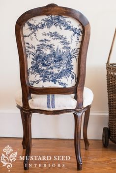 a chair with a blue and white pillow on top of it next to a wicker basket