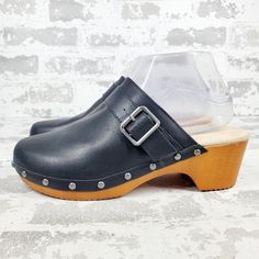 New Go Retro With This Easy-Wear Clog Featuring A Comfortable Memory Foam Footbed And Woodgrain Block Heel. Round Toe Pu Faux Leather Upper Buckle Accent Studded Trim Slip-On Style Memory Foam Footbed Block Heel Synthetic Upper, Lining And Sole Imported Black Low Heel Clogs, Black Low Heel Mules With Buckle Closure, Synthetic Closed Toe Clogs With Heel Loop, Black Low Heel Clogs With Removable Insole, Black Synthetic Clogs With Buckle Closure, Black Clogs With Buckle Closure And Flat Heel, Black Mules With Wooden Low Heel, Closed Toe Synthetic Clogs With Buckle Closure, Synthetic Closed Toe Clogs With Buckle Closure