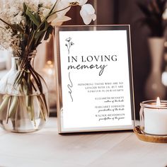 there is a vase with flowers on the table next to a sign that says in loving memory