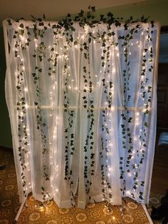 the curtain is decorated with lights and ivys on it's sides, along with white sheer curtains