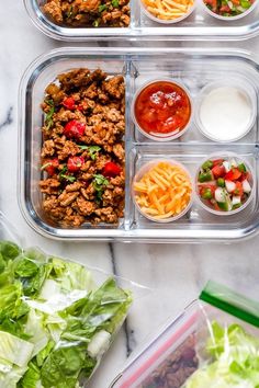 three plastic containers filled with food on top of a marble countertop next to lettuce