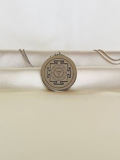 a white satin bag with a medallion on it