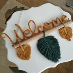 a welcome sign with two tassels hanging from it's side on a white plate