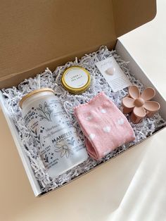 an open box with some items in it on a white table cloth and two flowers