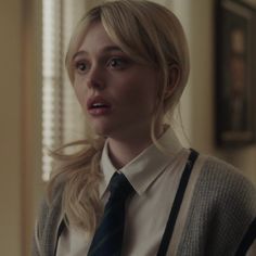 a woman with blonde hair wearing a white shirt and black tie in a living room