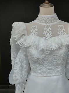 a white wedding dress with lace on the top and sleeves, sitting on a mannequin