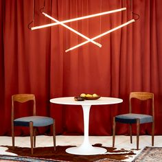 two chairs and a table in front of a red curtain with lights hanging from it