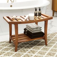 a wooden shelf with towels and soaps on it in front of a bathtub