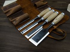 a set of knives with leather pouch on wooden table