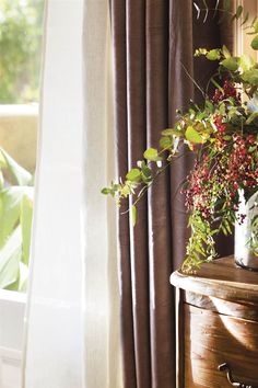 a vase with flowers sitting on top of a wooden table next to a window sill