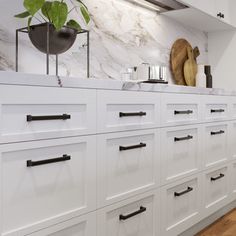 a kitchen with white cabinets and gold pulls on the handles, marble backsplash