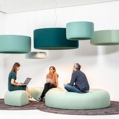 three people sitting on bean bag chairs with laptops in front of them and lamps hanging from the ceiling