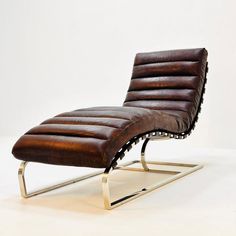 a brown leather chaise lounge chair sitting on top of a metal frame with a white wall in the background