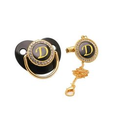 a pair of black and gold earring with the letter d on it, sitting next to a key