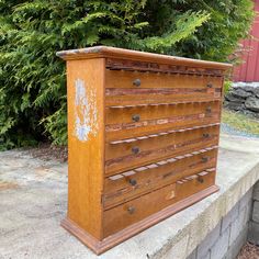 an old chest of drawers sitting on top of a cement slab next to some bushes