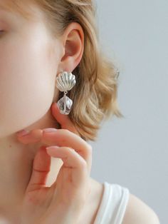 These stunning earrings create a captivating piece of jewelry with a unique combination of delicate seashells and sparkling white crystals. The seashells add a touch of natural beauty, while the white crystals add an elegant glow to the design. Perfect for adding a touch of originality and sophistication to any outfit, these earrings are sure to turn heads and be the center of attention wherever you go. Metal: Recycled Sterling Silver Plated On Brass Gemstone: White Crystal Earrings Dimensions: Length 45mm Single Weight: 8.5g Silver Dangle Jewelry With Shell, Shell Drop Earrings Jewelry Set, Shell Drop Earrings With Matching Set, Silver Ocean-inspired Earrings, Metal Shell Earrings For Gift, Ocean-inspired Silver Jewelry For Wedding, Silver Shell-shaped Earrings, Silver Shell Earrings For Pierced Ears, Elegant Shell-shaped Earrings