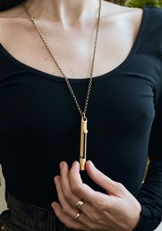 a woman wearing a black shirt holding a gold necklace