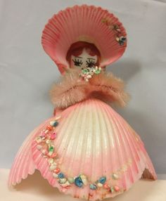 a doll is dressed in a pink dress and hat with pearls on it's head