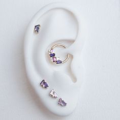 an ear with three different colored stones on it and one is in the shape of a ring