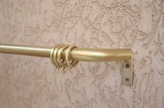 a close up of a gold curtain rod with rings on the end and hooks attached to it