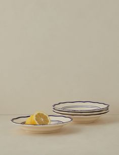 two plates with lemon slices on them sitting next to each other in front of a white wall