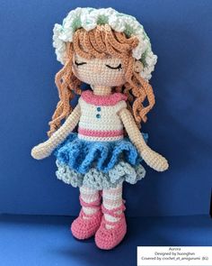 a crocheted doll is posed on a blue background