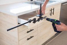 a man is using a power drill to fix a kitchen cabinet