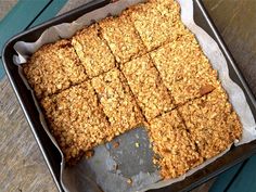 a pan filled with granola squares sitting on top of a wooden table next to a knife