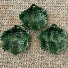 three green leaf shaped dishes sitting on top of a carpet