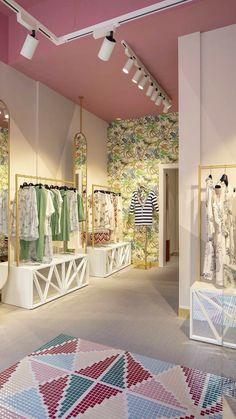 the interior of a clothing store with clothes hanging on racks and colorful rugs in front of them