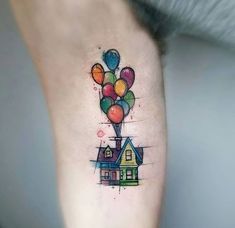 a house with balloons tattoo on the side of its leg and it's legs