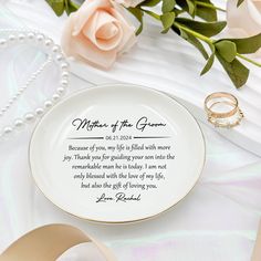 a plate with a wedding poem on it next to some flowers and two gold rings