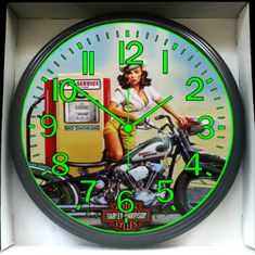 a neon clock with a woman on a motorcycle in front of a gas station sign