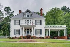 a large white house sitting on top of a lush green field