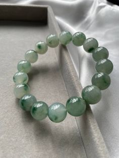 Item Code: JBD226001  Burmese Grade A Jadeite Jade Carved out from a single stone, this piece of jadeite bead bracelet is one of the uncommon ones in the market. Great translucency due to it being the icy type jadeite. One notable feature is the fine texture of each of the beads. The color of this bead bracelet varies according to the lighting of the surrounding but its true color which can be seen under natural lighting as taken in the last picture is misty green. Each of the beads has green floating flowers which is an added value to the piece. All our photos were taken under natural light settings to showcase the true essence and colours of the pieces. We condemn the uses of any photo editing softwares to alter the colours of the pictures taken. We try to capture the true colours of the Elegant Jade Crystal Bracelet With Round Beads, Green Gemstone Beads Round Bracelet, Green Gemstone Beads Round Bracelets, Green Jade Gemstone Beads Bracelets, Green Aventurine Round Beads Bracelets, Jade Gemstone Crystal Bracelet, Jade Gemstone Beads Bracelets, Green Jade Bracelets With Round Beads, Aventurine Gemstone Beads Bracelets