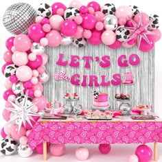 a pink table topped with lots of balloons and cake next to a sign that says let's go girls