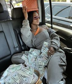 a woman sitting in the back seat of a car with money on her head and purse over her head