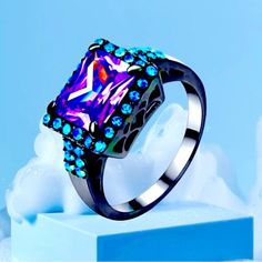 a purple and blue ring sitting on top of a block of ice with snow in the background