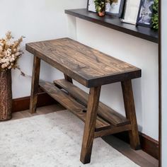 a wooden bench sitting next to a wall with two pictures on it's shelf